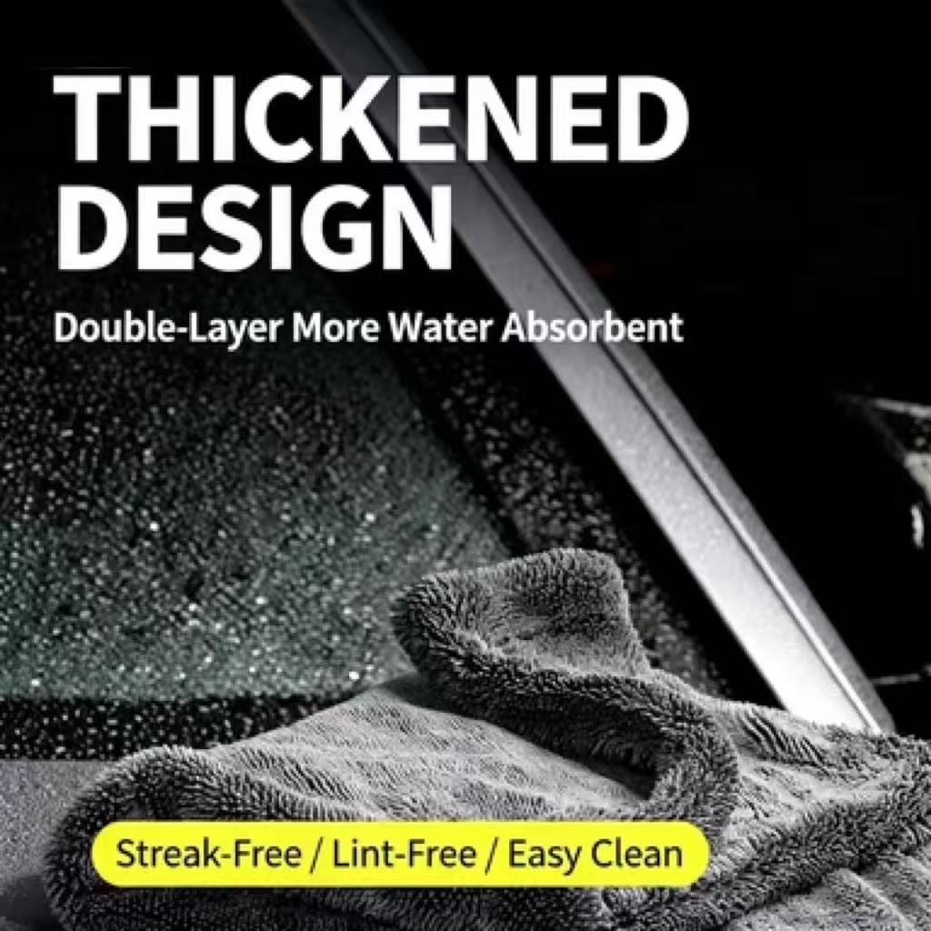 A close-up of a thick, textured gray microfiber cleaning cloth draped over a wet car window, with bold white text reading 'THICKENED DESIGN' and a yellow banner at the bottom that says 'Streak-Free / Lint-Free / Easy Clean'.